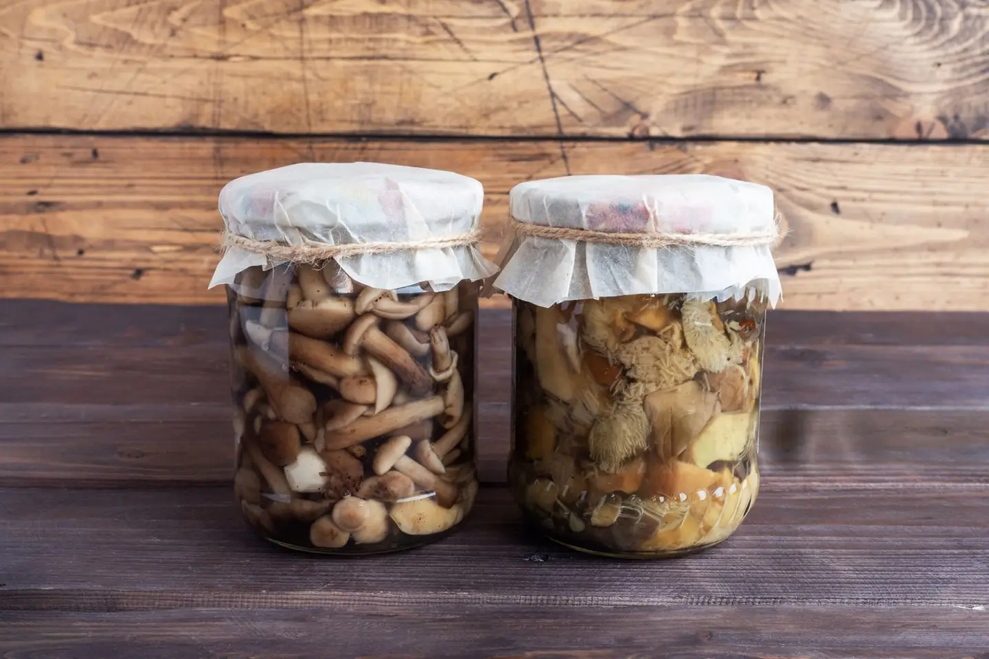 Fermented mushrooms in two jars on a wooden desk