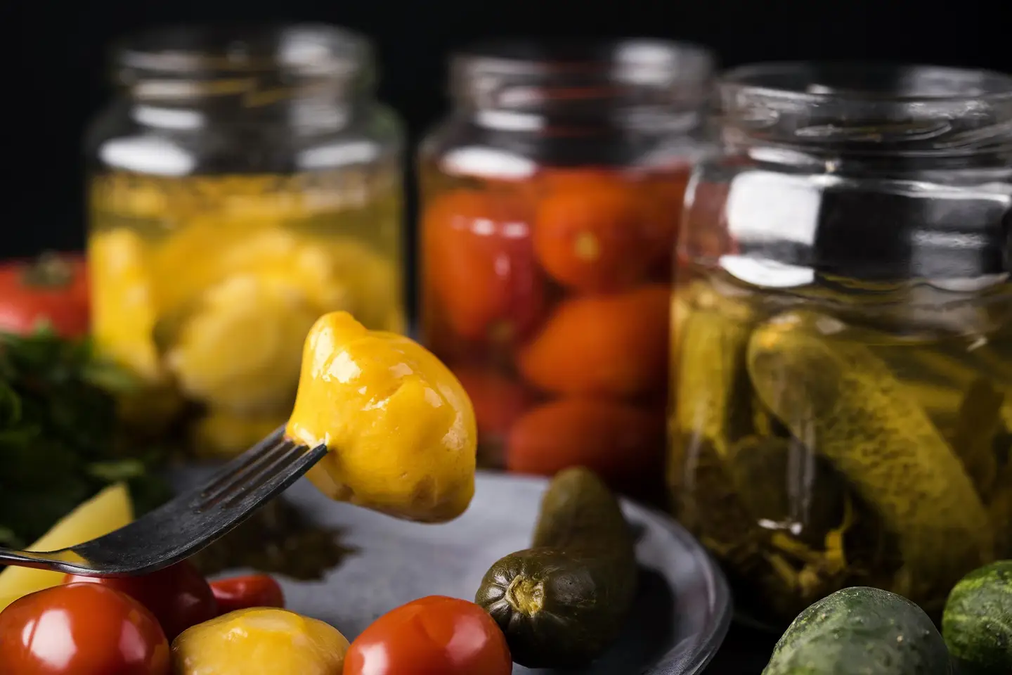 Delicious fermented vegetables prepared in jars and unprepared on plate