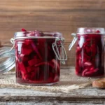 Fermented beetroot slices in two jars on a wooden desk