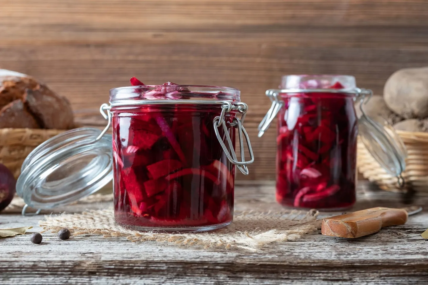 Fermented beetroot slices in two jars on a wooden desk