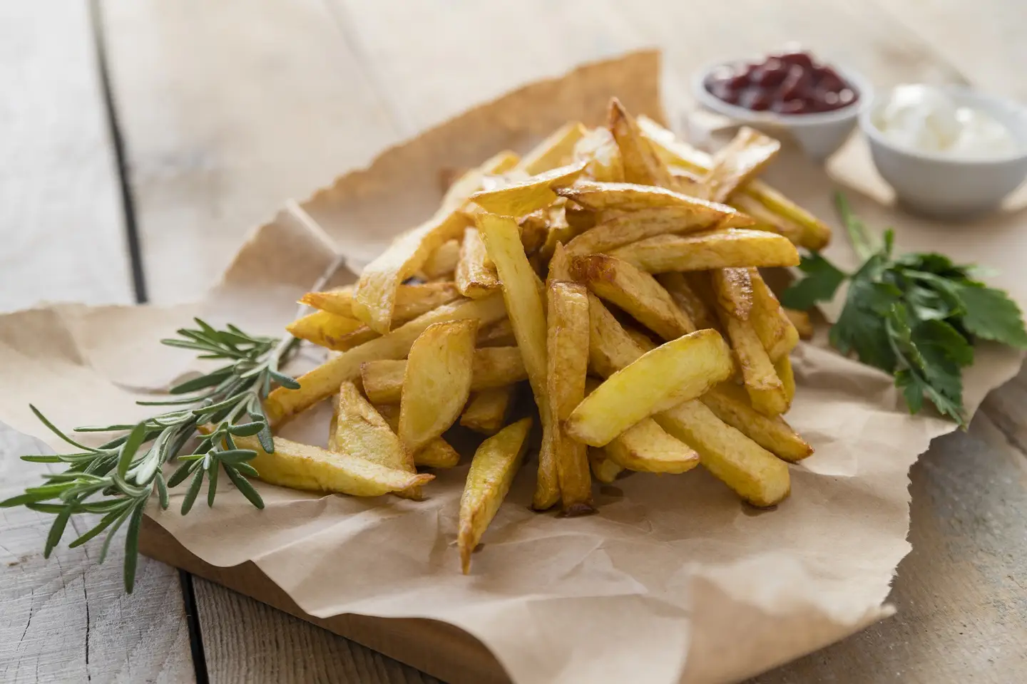Delicious spiced fermented potato fries with herbs on a paper and wooden desk